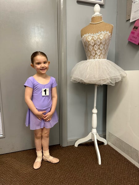 Emilai in ballet costume standung beside mannequin wearing a ballerina's tutu