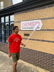 Man in DKMS t-shirt carrying a giant swab