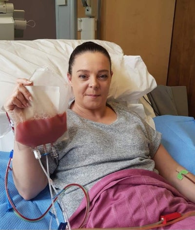 Louise lying in on hospital bed holding her stem cell donation