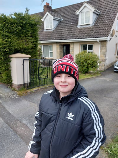Bobby standing in the street dressed in 'United' bobble hat and black jacket
