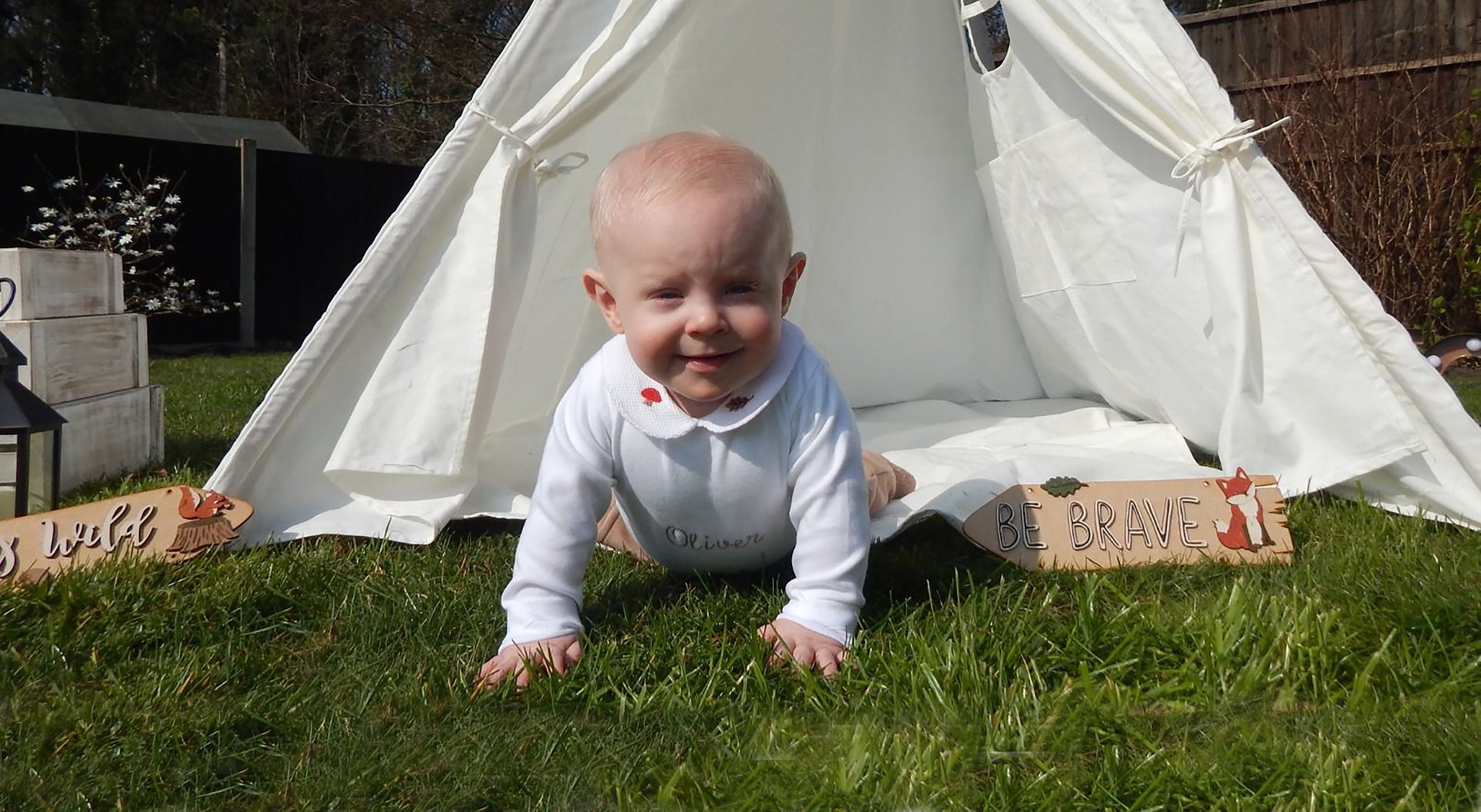 Olive as a baby crawling from a white play tent in the garden
