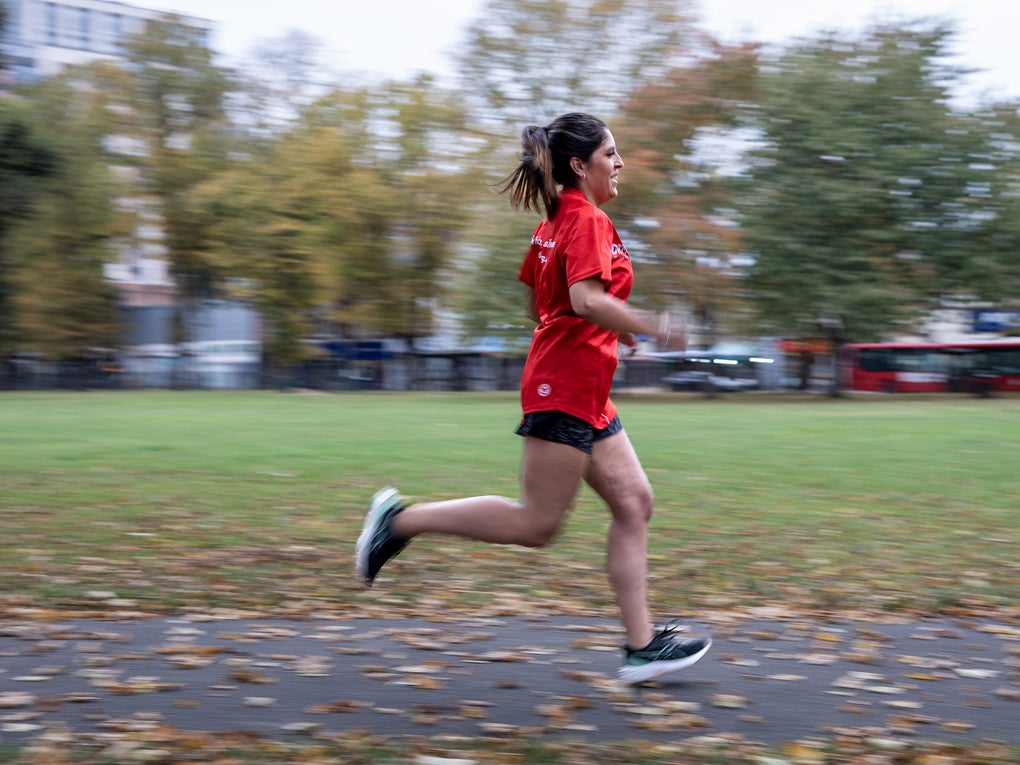 Woman in red top running through a park Woman in red top running through a park