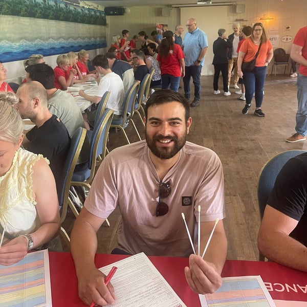 Man smiling and holding swabs at a donor registration event Man smiling and holding swabs at a donor registration event