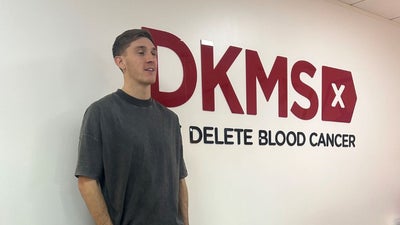 Jimmy Dunne at the DKMS UK office standing by the Corporate signage