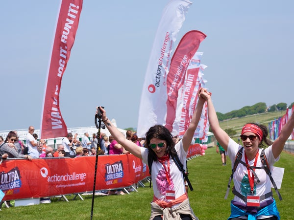 Two women cross the London to Brighton finish line with their hands in the air