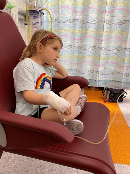 Emilia sitting with her feet up on a hospital chair wearing a rainbow design t-shirt