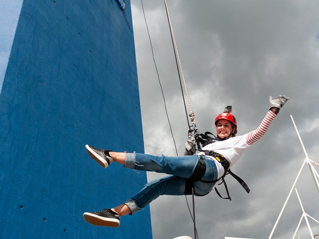 Sally on a harness waving to the camera as she abseils the Spinnaker Tower.  Sally on a harness waving to the camera as she abseils the Spinnaker Tower.
