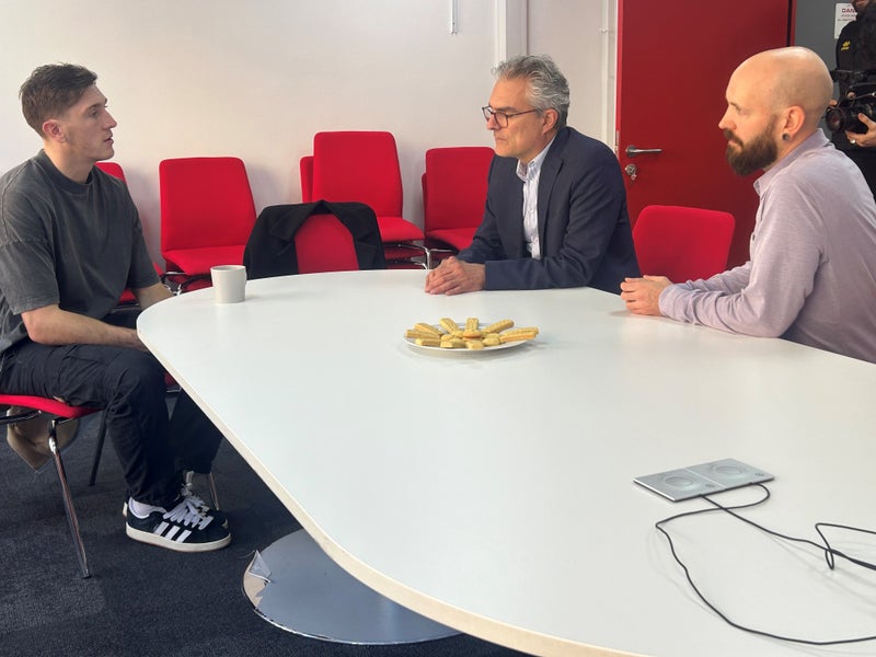 Jimmy Dunne sitting in a meeting room with the DKMS UK CEO and Head of Marketing