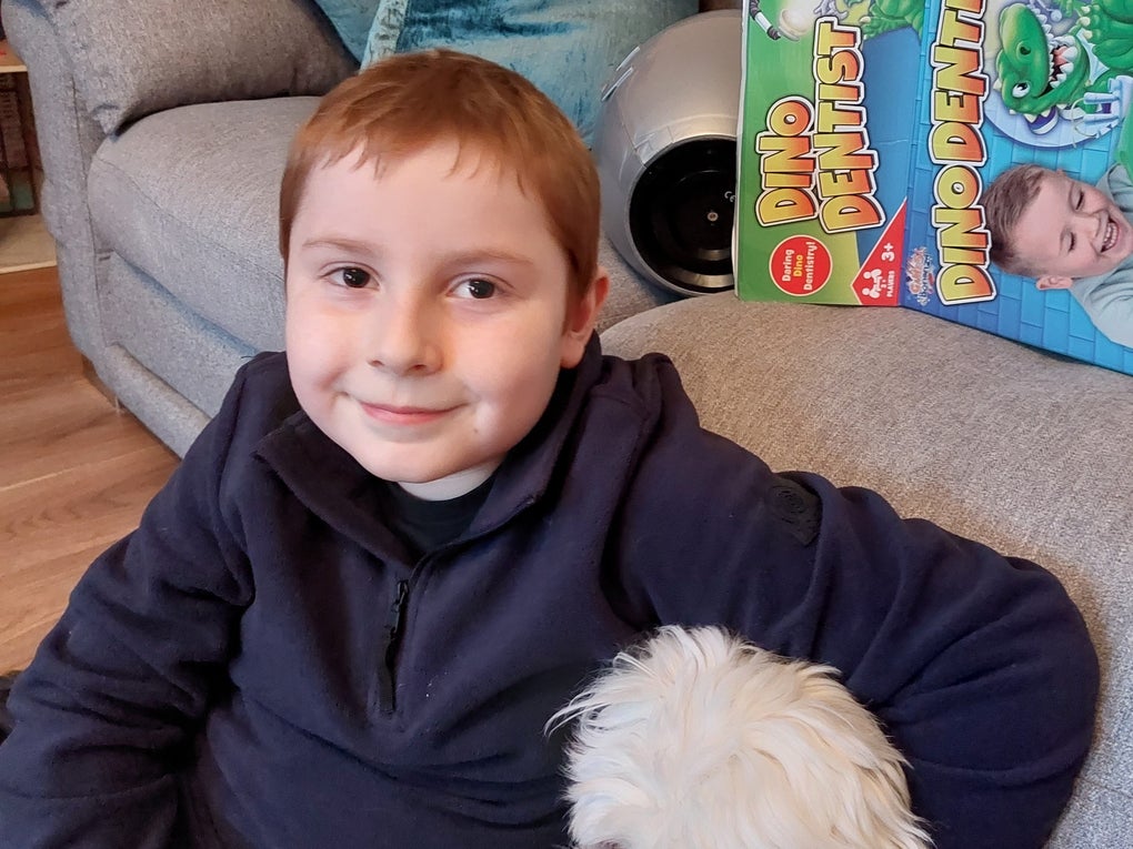 Bobby sitting on floor in front of as sofa cuddling a white dog Bobby sitting on floor in front of as sofa cuddling a white dog