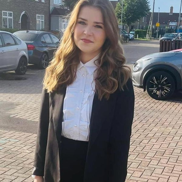Amber dressed in black suit standing in a car park Amber dressed in black suit standing in a car park