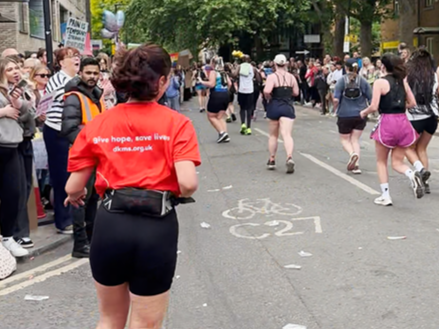 Girl wearing DKMS Running top runs in Half marathon, with other runners and supporters in the background Girl wearing DKMS Running top runs in Half marathon, with other runners and supporters in the background