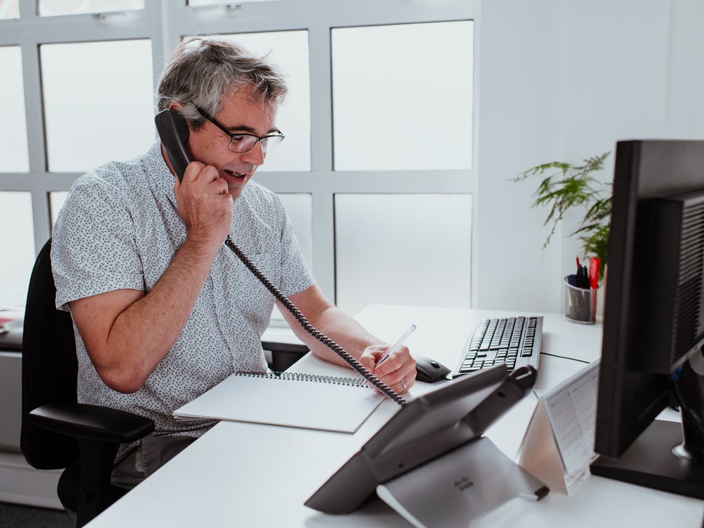 A man sat at a desk on the telephone A man sat at a desk on the telephone