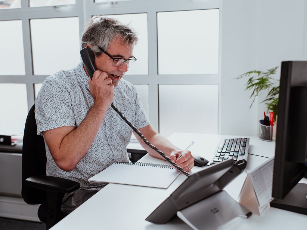 A man sat at a desk on the telephone A man sat at a desk on the telephone
