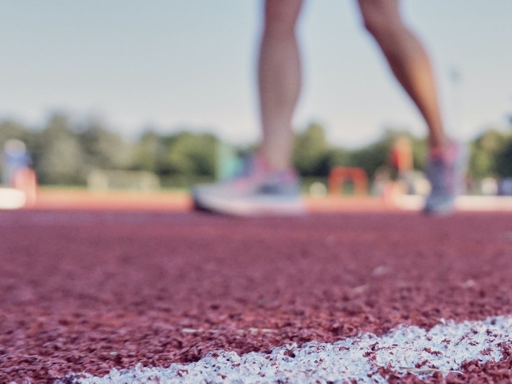 Feet and legs of an athlete on a red running track Feet and legs of an athlete on a red running track