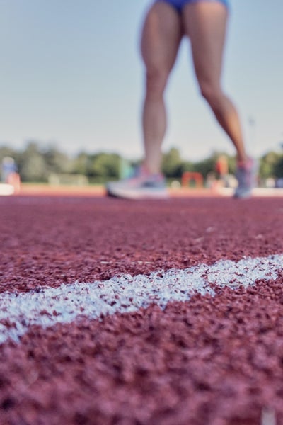 Feet and legs of an athlete on a red running track Feet and legs of an athlete on a red running track