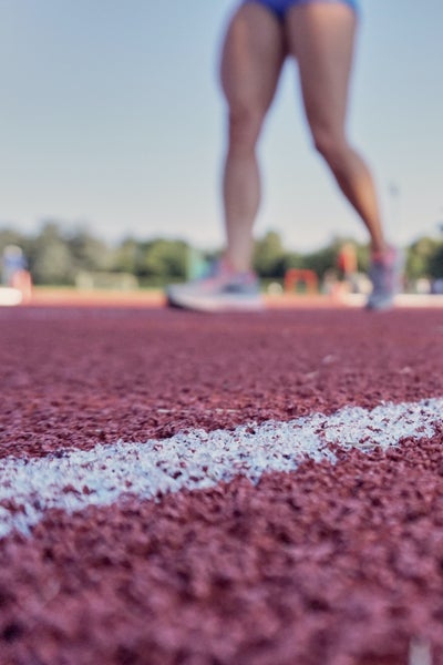 Feet and legs of an athlete on a red running track