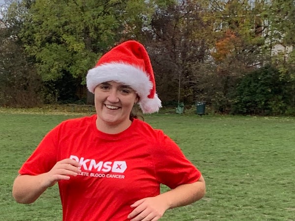 Woman running in Santa hat and DKMS top
