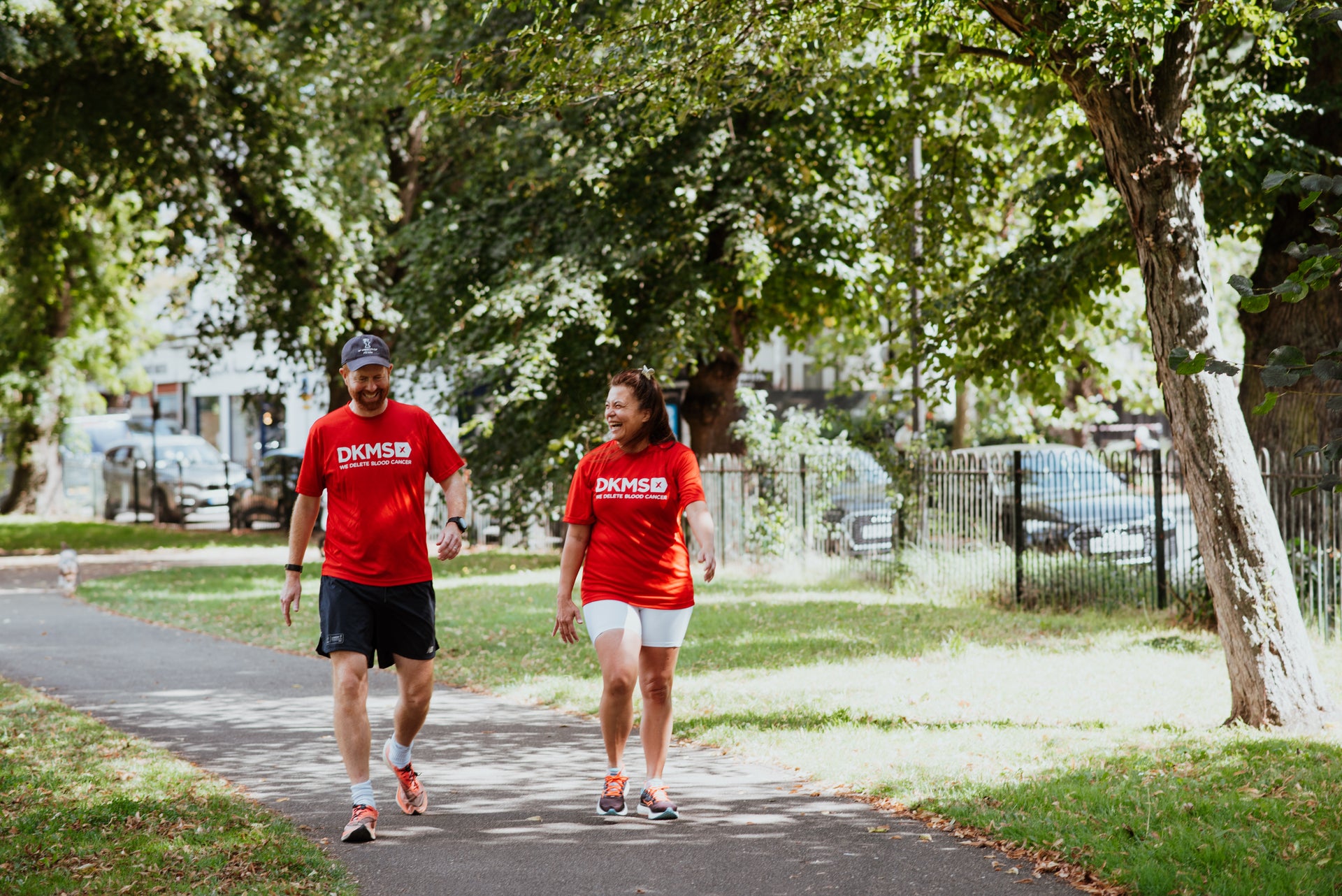 Two people in DKMS t-shirts walking in the park