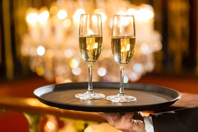 Two champagne glasses on a tray against a fairylights background