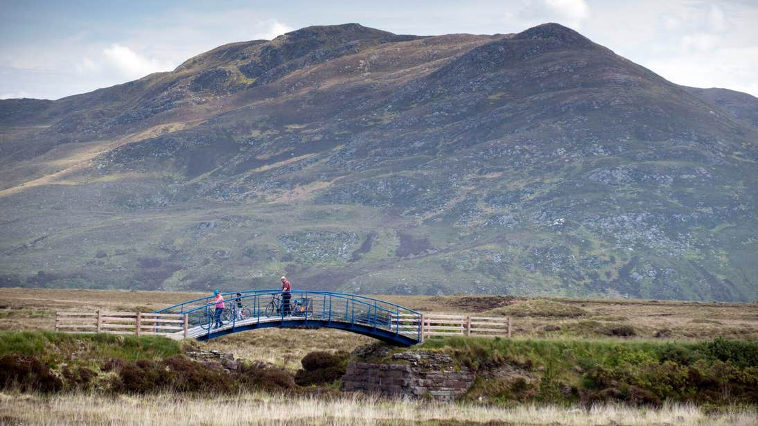 Family crossing a bridge on bikes on The Great Western Greenway in Mayo