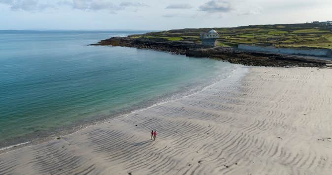 Two people walking on Kilmurvey Beach on Inis Mór in County Galway.
