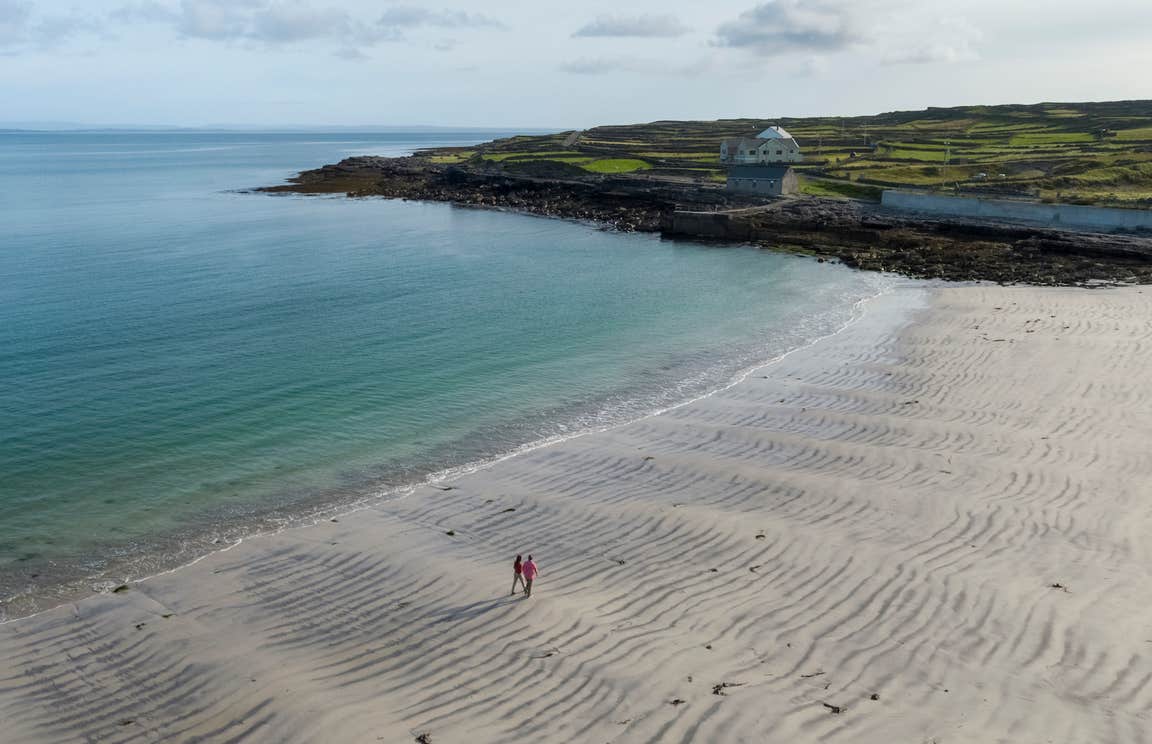 Two people walking on Kilmurvey Beach on Inis Mór in County Galway.