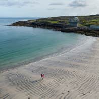 Two people walking on Kilmurvey Beach on Inis Mór in County Galway.