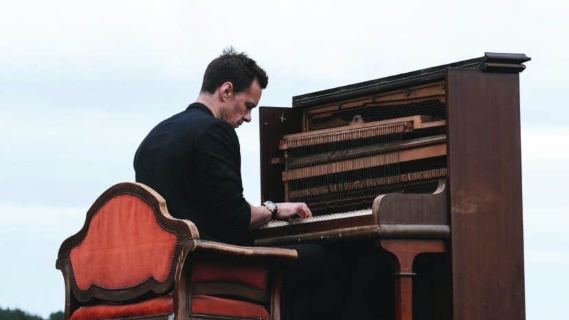 Niall Breslin playing an upright piano outdoors