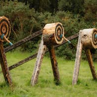 Three wooden targets in a field with an axe in the middle of each