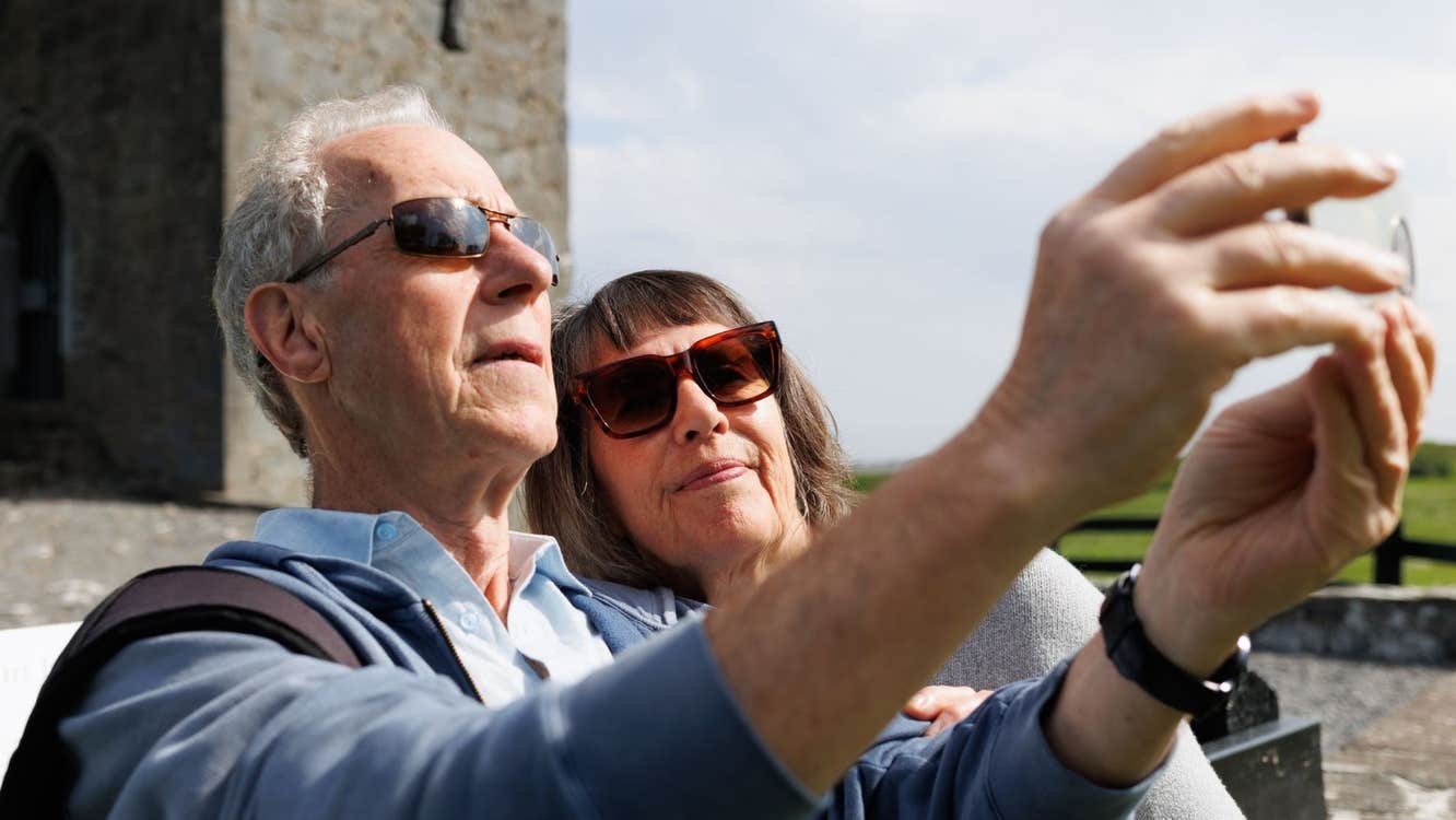 Two people wearing sunglasses taking a picture in front of a castle