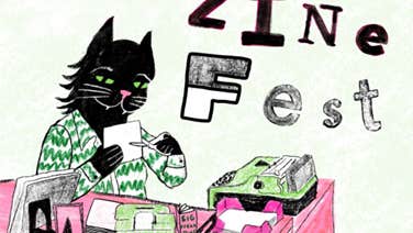 A cat at a desk, making a zine.