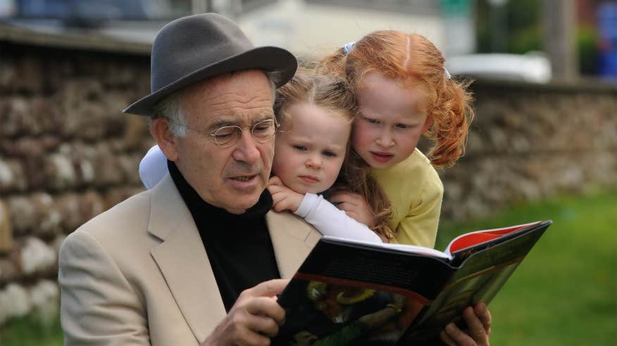 A man reading a book to two kids