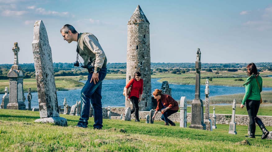 Four people exploring the Clonmacnoise monastic site in County Westmeath.