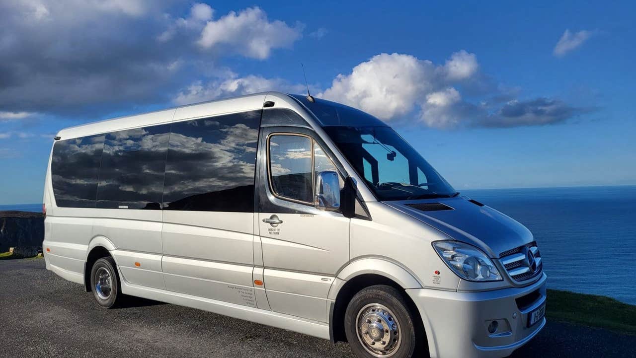 Mercedes tour bus with sea and blue sky in the background