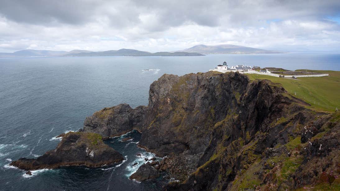 A view of a lighthouse on a cliff and waves crashing against the rocks below at Clare Island Lighthouse, Mayo