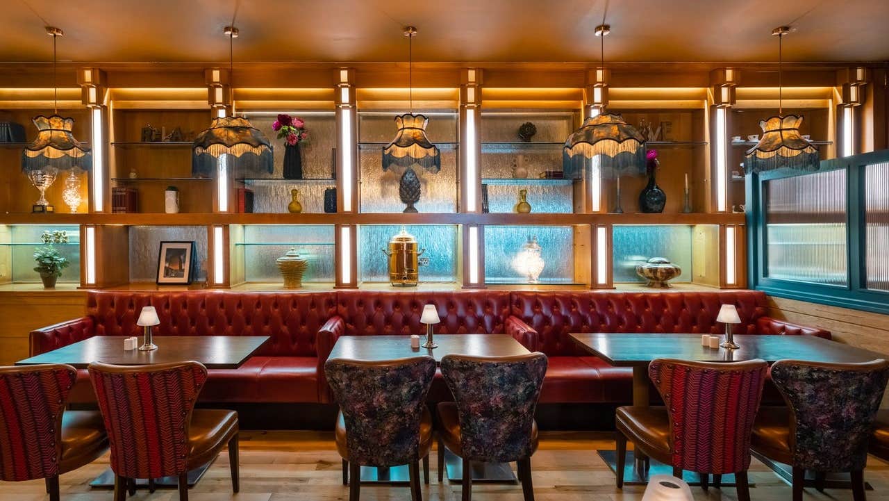 Dining tables and chairs in a restaurant with mirrors and lighting behind