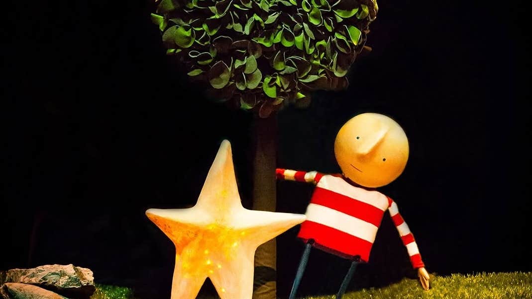 How To Catch A Star, a puppet with bald head and stripy top, swinging from a tree, beside a large gold star.