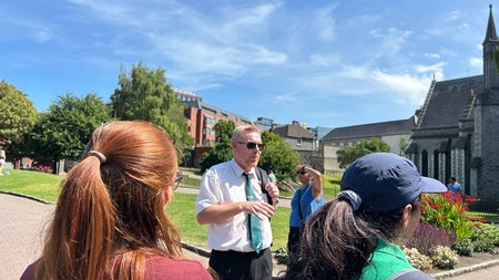 Two people listening to a tour guide speak