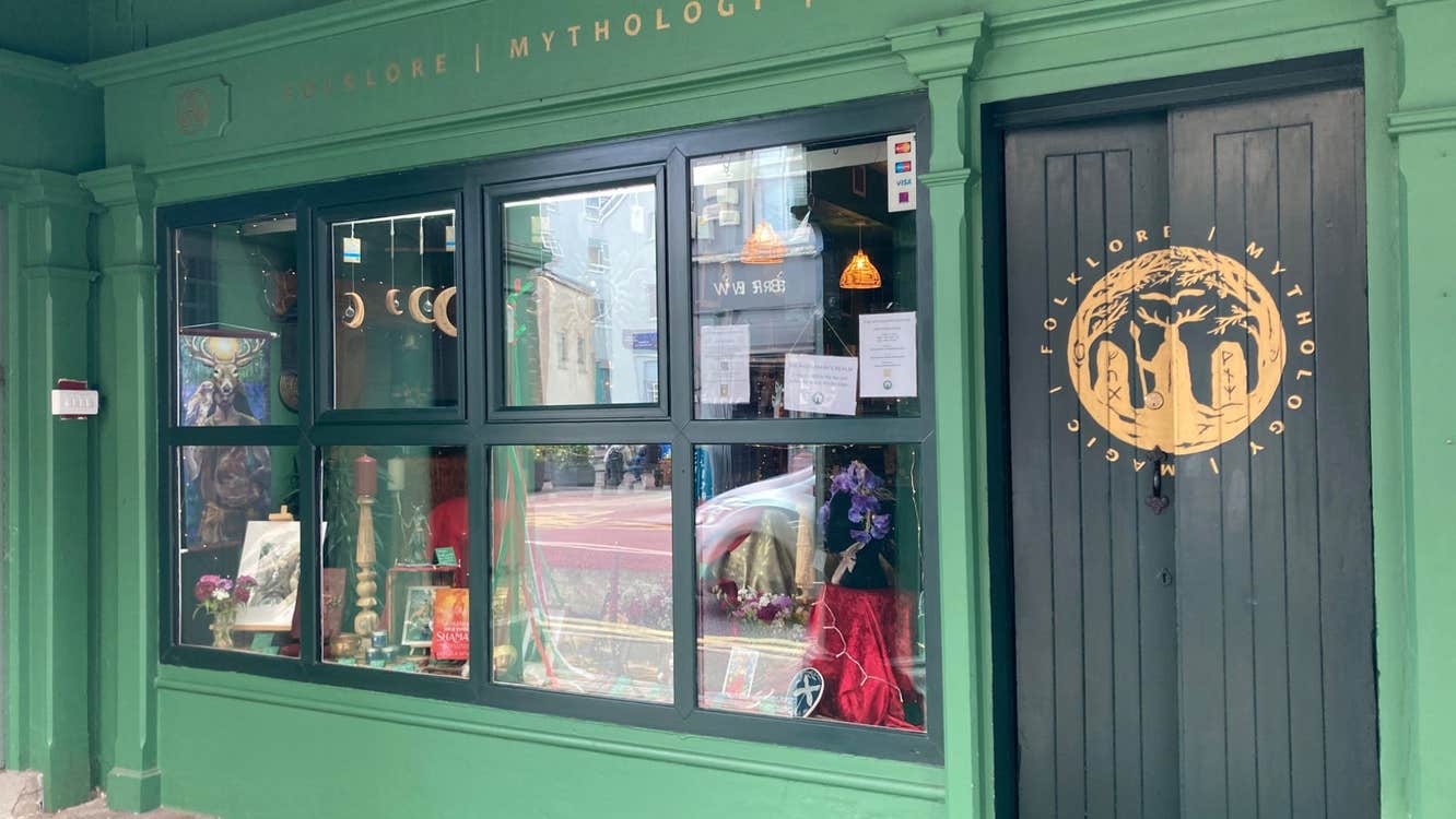 The exterior of a shop front painted green with gold lettering signage