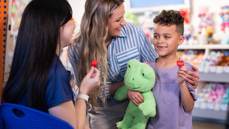 Child and adults with a green bear and red heart