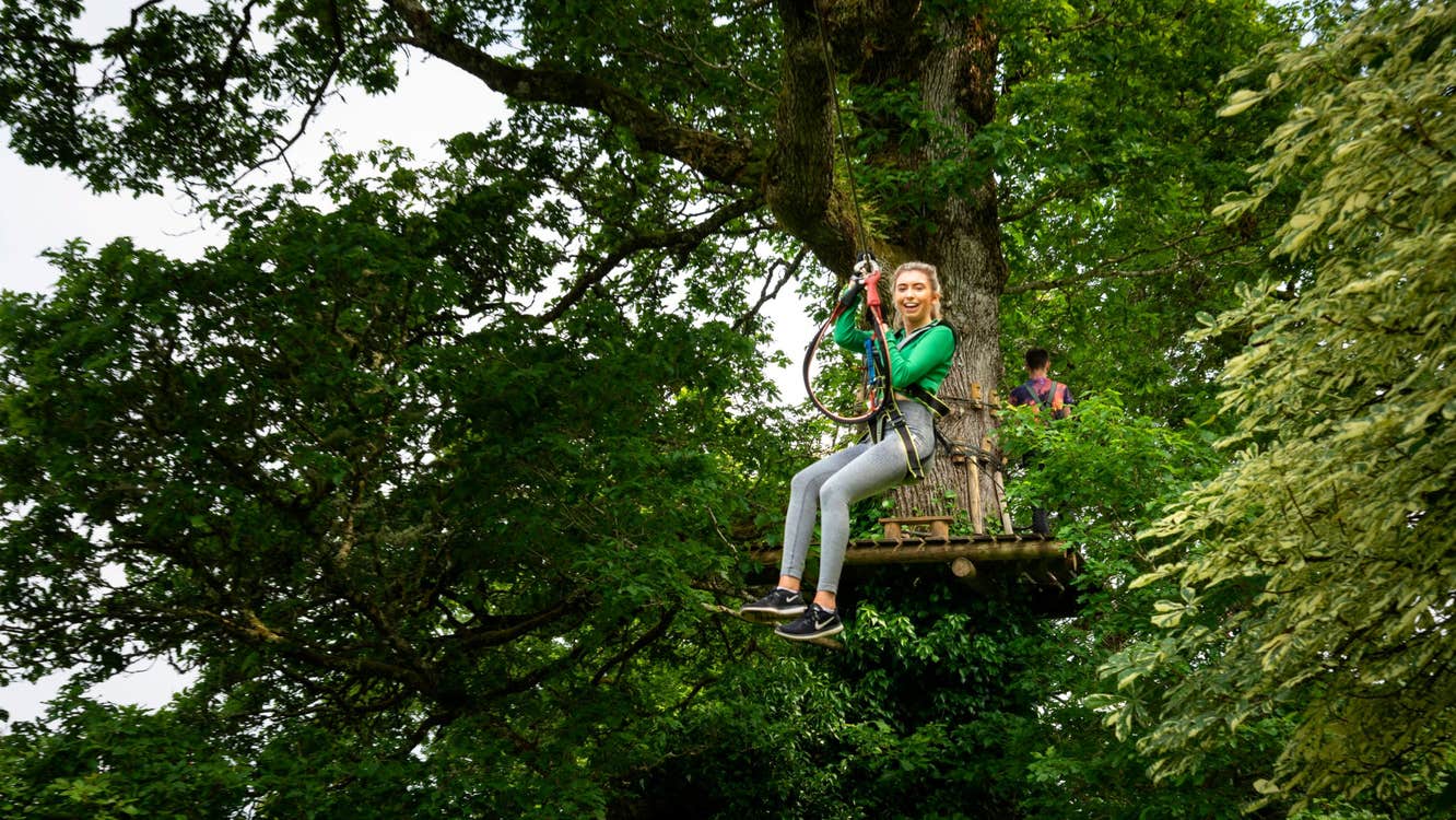Girl in a green jumping sliding down a zipline in Roscommon