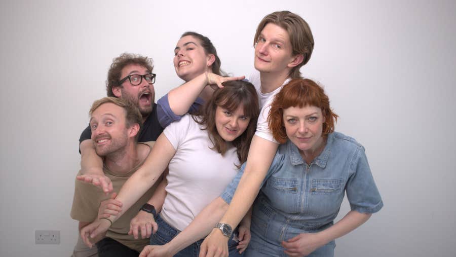 A group of 6 people standing, intertwined with each other.