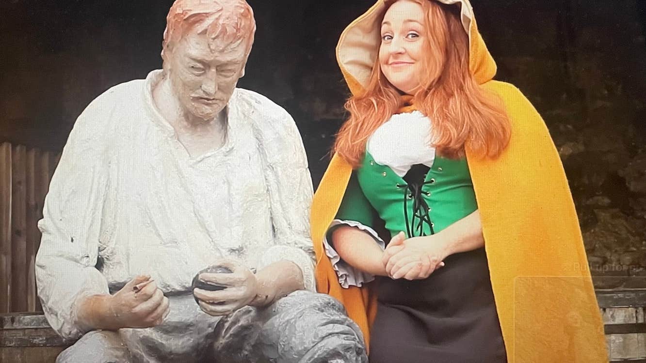 Person in a yellow cloak sitting next to a mannequin wearing a white shirt