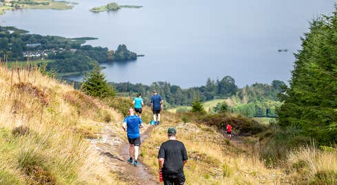 Amazing views of Quest Lough Derg, people on a track downhill with lough in the background.