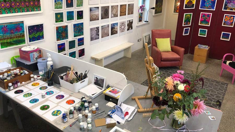 Desk with artist supplies and works in progress in an artist's studio