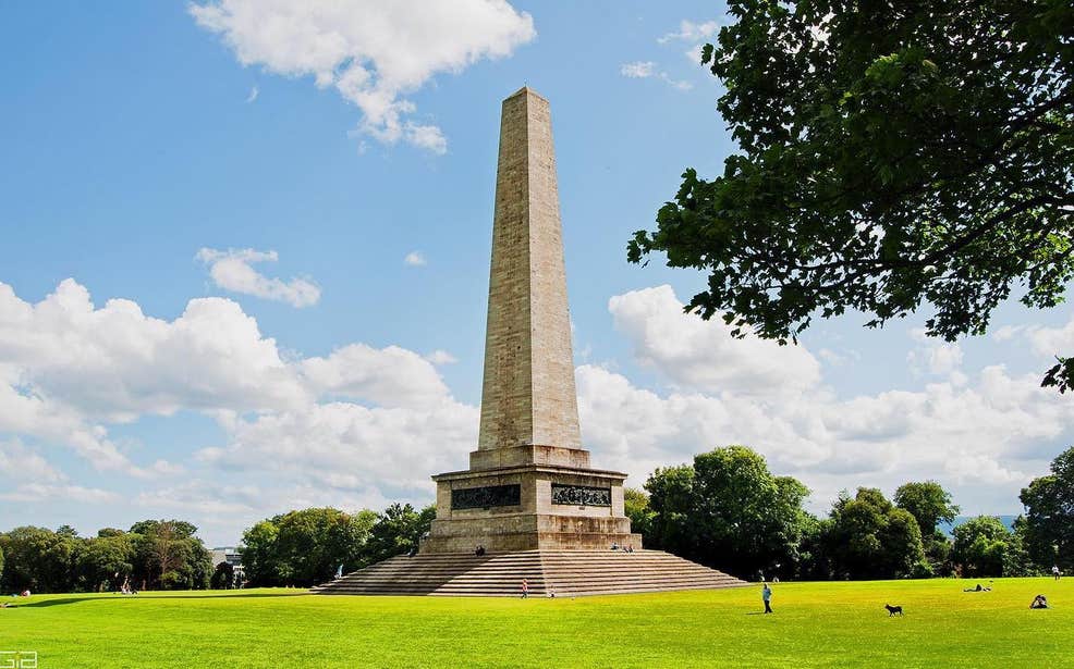 Wellington monument in Phoenix Park on a sunny day with blue skies and bright green grass surrounding it.