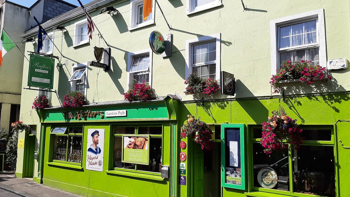 A brightly coloured pub exterior with floral baskets along the walls and windows