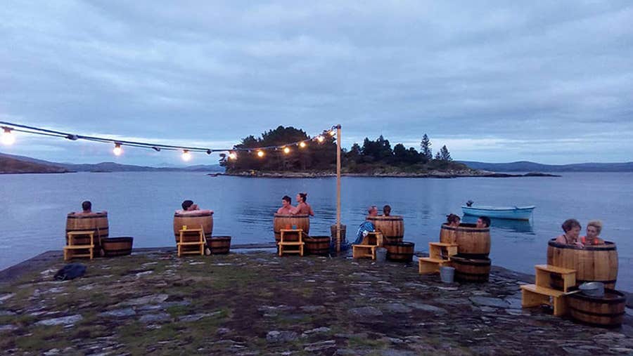 A group of people in several seaweed baths enjoying the sunset