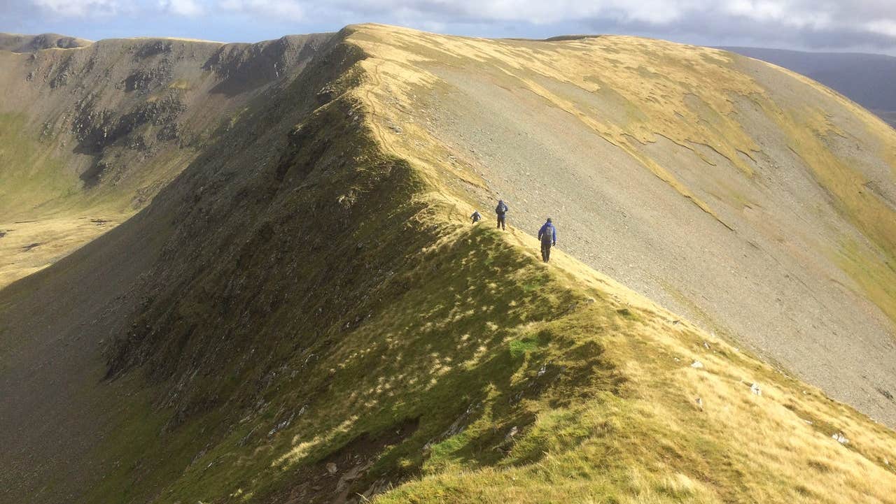 Two people walking along a mountain ridge
