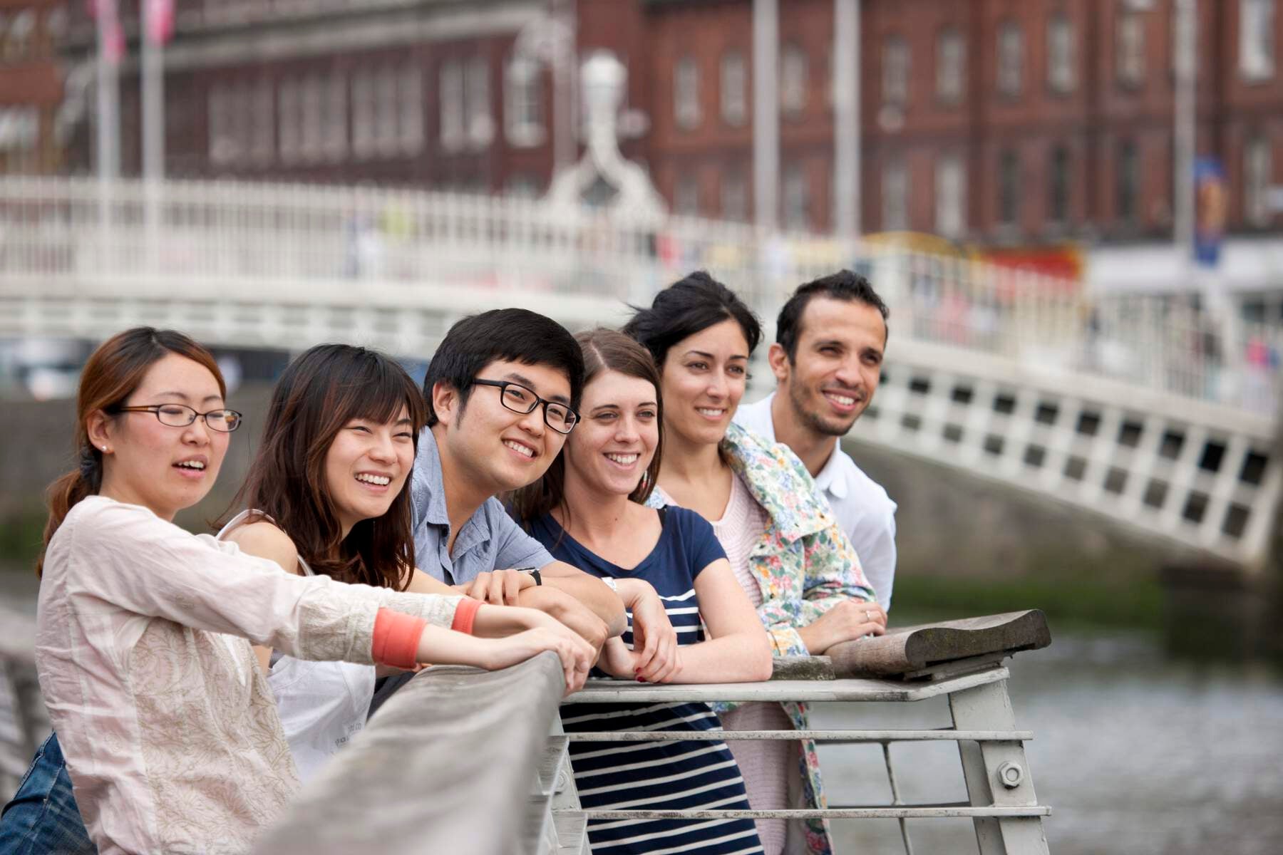 Group of international friends looking out at the River Liffey in front of the Ha'Penny Bridge